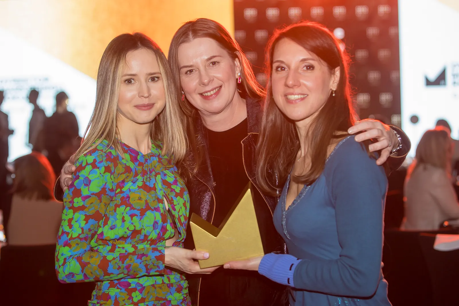 Three winners with a statuette at a Gala table